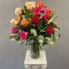 Two dozen mixed color roses arranged in a tall clear glass vase