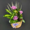 A decorative container is filled with assorted green plants, fresh cut flowers