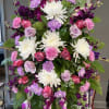 A sympathy easel with purple, lavender and white flowers. 
