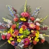 A funeral arrangement in a urn style vase full of bright exquisite