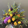 A urn style vase arrangement with bright yellow, green, orange and blue