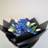 White tulips paired with vivid blue baby&rsquo;s breath, wrapped in matte black
