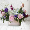 This arrangement includes white hydrangeas, pink roses, white lilies, purple lisianthus, and