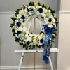 WHITE CIRCULAR FUNERAL ARRANGEMENT WITH BLUE TOUCHES