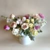 A ceramic vase filled with white hydrangeas, pink roses and lisianthus make