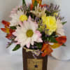 A cute, petite floral arrangement on top of a 12 oz. Harvest