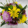 A cute, petite floral arrangement on top of a 12 oz. Harvest