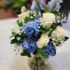 White Roses, blue carnations, blue delphinium in a vase