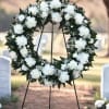 An 18&rdquo; round wreath with white carnations and babies breath 