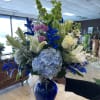 This arrangement is composed of blue thistle, blue hydrangeas, white lilies, white