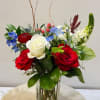 A vibrant mix of red roses, white blooms, and soft blue accents.