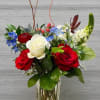 A vibrant mix of red roses, white blooms, and soft blue accents.