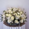 The Elegant White Serenity arrangement features premium white roses, ranunculus, scabiosa, and