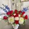 A red, white, and blue flower arrangement in a large base makes
