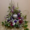 A beautiful arrangement of purples and greens that delicately surround the urn.

Please