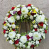 Beautiful funeral spray wreath featuring white chrysanthemums, yellow roses, pink carnations, and