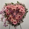 This is a heart-shaped floral arrangement featuring a mix of pink and
