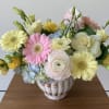 A pastel flower arrangement in a ceramic white vase with premium flowers