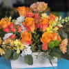 A modern Floral arrangement featuring vibrant orange roses in a rustic wooden
