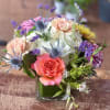 A delightful and fluffy mini arranged in a clear glass vase.