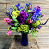 A taller blue vase arrangement with a collection of deep blue, violet