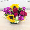 A summery vase of sunflowers, roses, spray roses and berries in bright