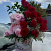 Sweet arrangement with roses, delicate blooms, and a cuddly teddy bear.