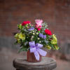 A petite textured jar style vase in assorted spring colors is filled