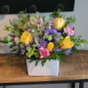 This is a bright and cheerful flower arrangement in a white rectangular