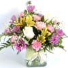 This clear cube vase is filled with white roses, daisies, carnations alstroemerias