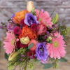 An assortment of Roses, Gerbera Daisies, Tulips, and Lilies in a vase.