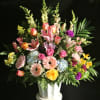 mixed flowers in a rainbow of colors arranged in a mache basket