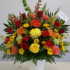 red, yellow, and orange flowers arranged in a mache basket