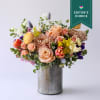 Cheerful seasonal spring blooms and delicate accents are arranged in a composed
