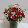 Fifteen short roses arranged with greens in a short clear vase.