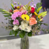 With a playful mix of bold yellow lilies, coral roses, cheerful mums