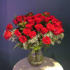 Dozens of velvety red roses stand tall in a clear glass vase