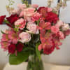 Clear vase with pink roses, red and pink alstromeria flower, pink larkspur