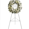 White blooms and greenery decorate on a ring stand easel.
Picture is a