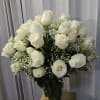 This is a classic white rose bouquet arranged in a clear glass