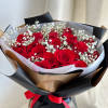 A round bouquet of roses and baby&#039;s breath, wrapped in black paper.