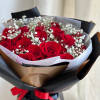A round bouquet of roses and baby&#039;s breath, wrapped in black paper.