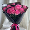 A front-facing bouquet of roses with layered paper accents, wrapped in black