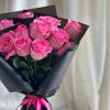 A front-facing bouquet of roses with layered paper accents, wrapped in black