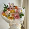 A round bouquet with yellow, coral, peach, pink, white, and green flowers