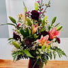 Stargaser lillies and deep plum Carnations in a purple vase