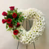 This Open Heart Wreath on an Easel includes White Flowers with Red