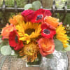 Arrangement of bright summer reds, yellows &amp; orange clusters with sunflowers, anemones