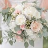 A graceful arrangement of creamy white and blush roses, delicate peonies, and