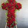 A graceful cross of red roses, honoring a life with deep love